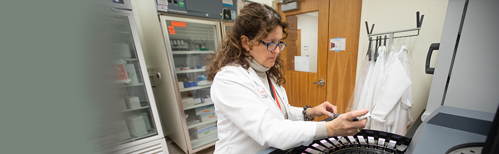 woman with curly hair in a lab coat working at a centerfuge 