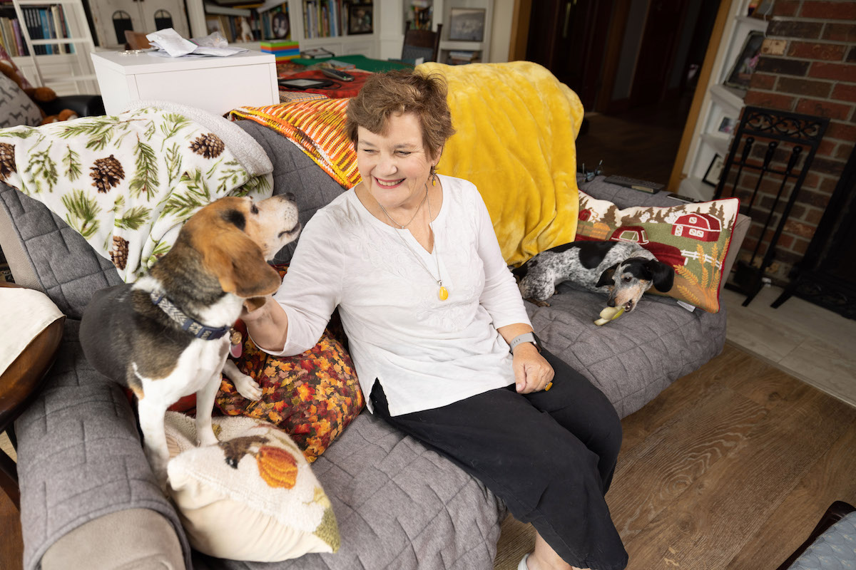 Margarete sitting on her couch at home with two dogs