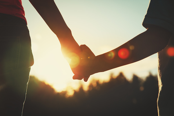 silhouette of parent and child holding hands at sunset