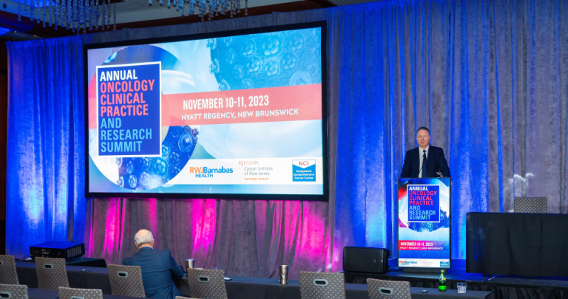 Speaker stands at podium at Annual Oncology Clinical Practice and Research Summit