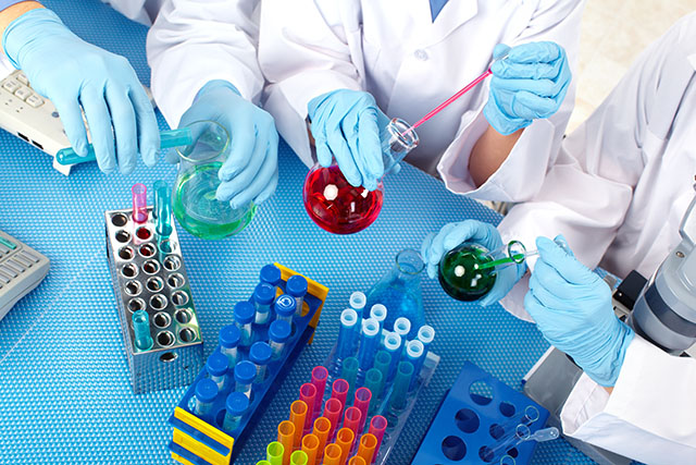 Laboratory equipment surrounded by researchers hands