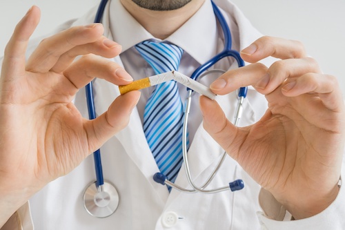 man in white doctor's coat breaking cigarette in half