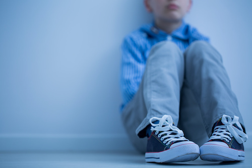 young child sitting against a wall