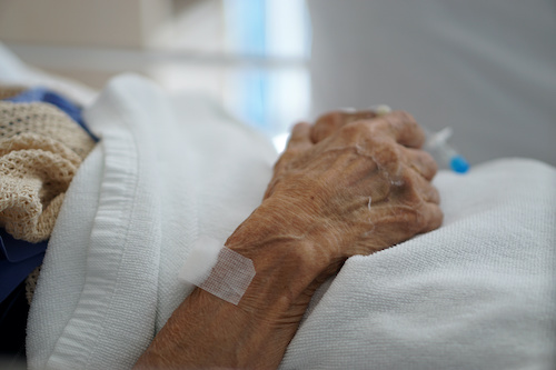 hand of elderly person in hospital bed