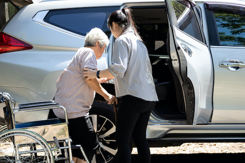 younger woman helping an older woman into a car