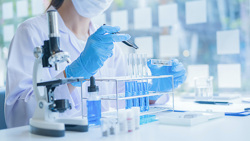 Medical or scientific researcher or man doctor looking at a test tube of clear solution in a laboratory