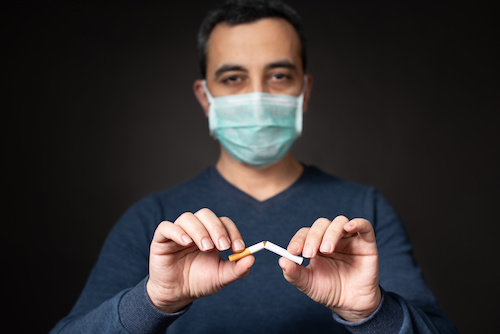 man wearing a mask, breaking a cigarette