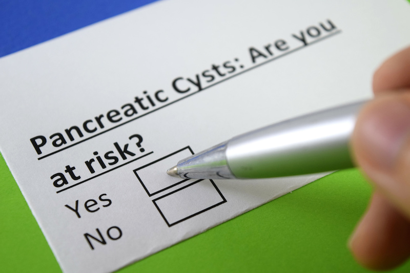 Hand holding a pen posed to fill out health questionnaire about pancreatic cysts