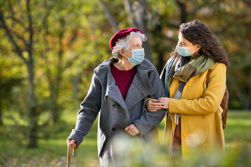 older women being supported by younger women walking through the park