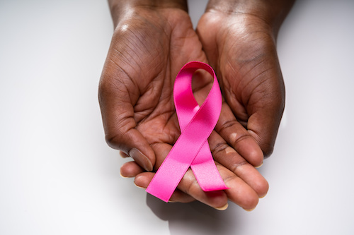 a black woman's hands holding a pink breast cancer ribbon