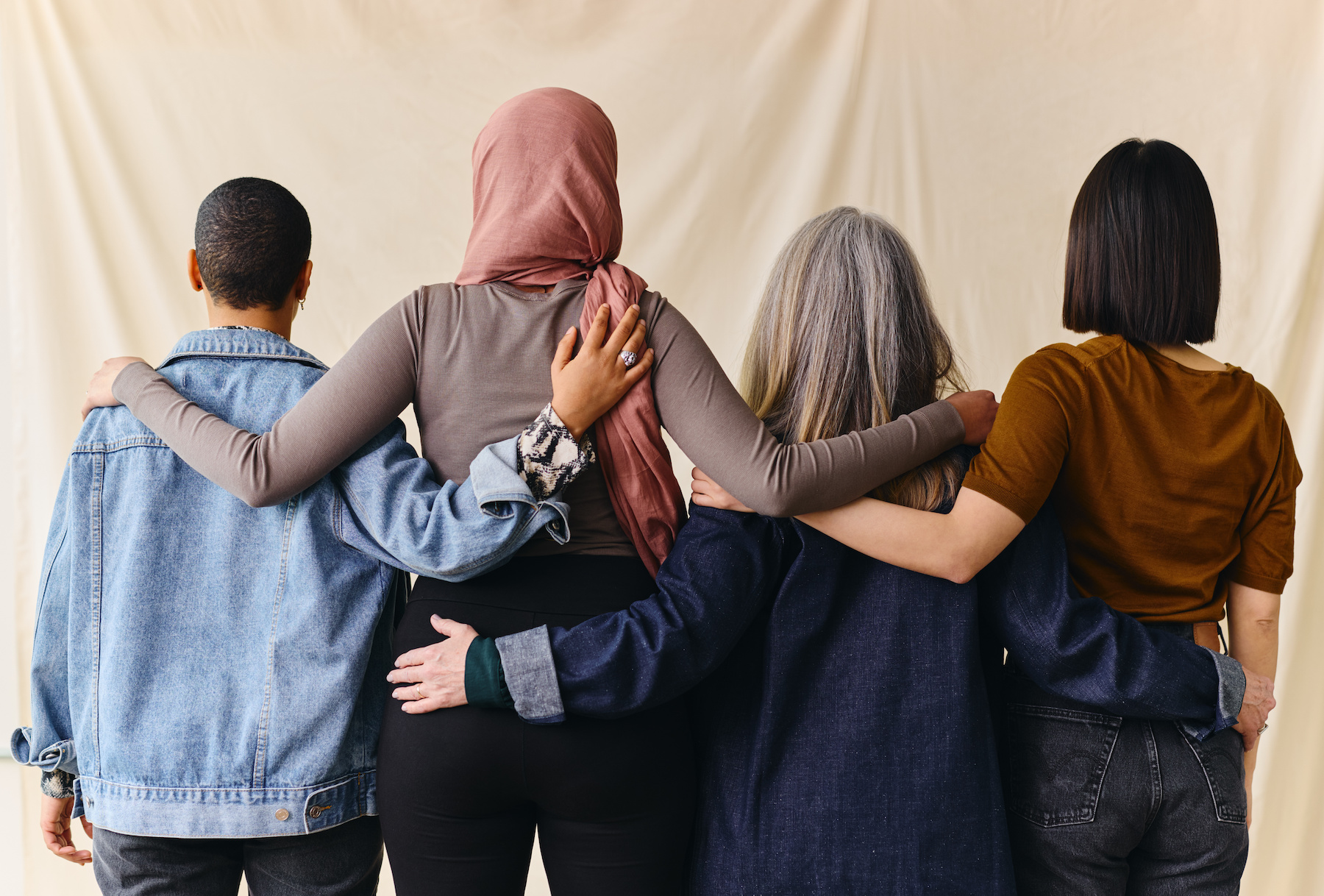 rear view of four women linking arms