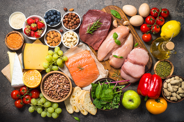 an array of healthy foods like nuts, lean meats, etc. on a slate background