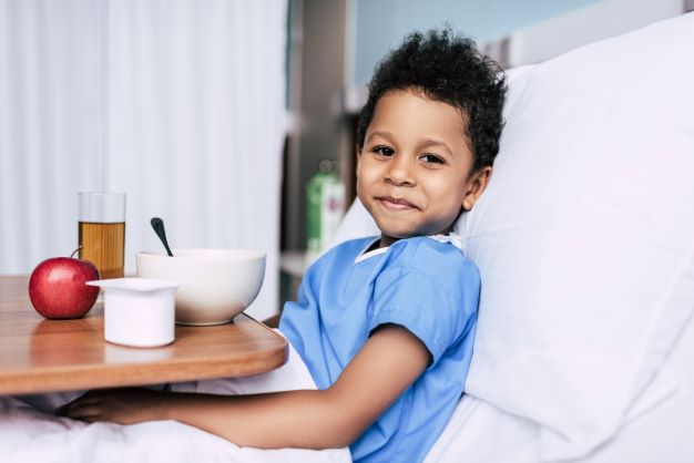 Young boy in hospital bed eating apple
