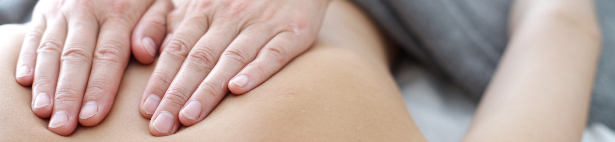 Close up of hands performing massage therapy on patient's bare back