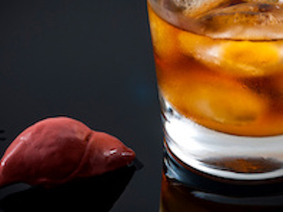 Liver sits next to glass of whiskey on black tabletop