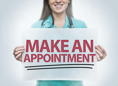 woman in scrubs holding sign saying make an appointment