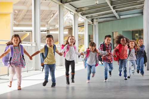 group of children holding hands walking down school hallway