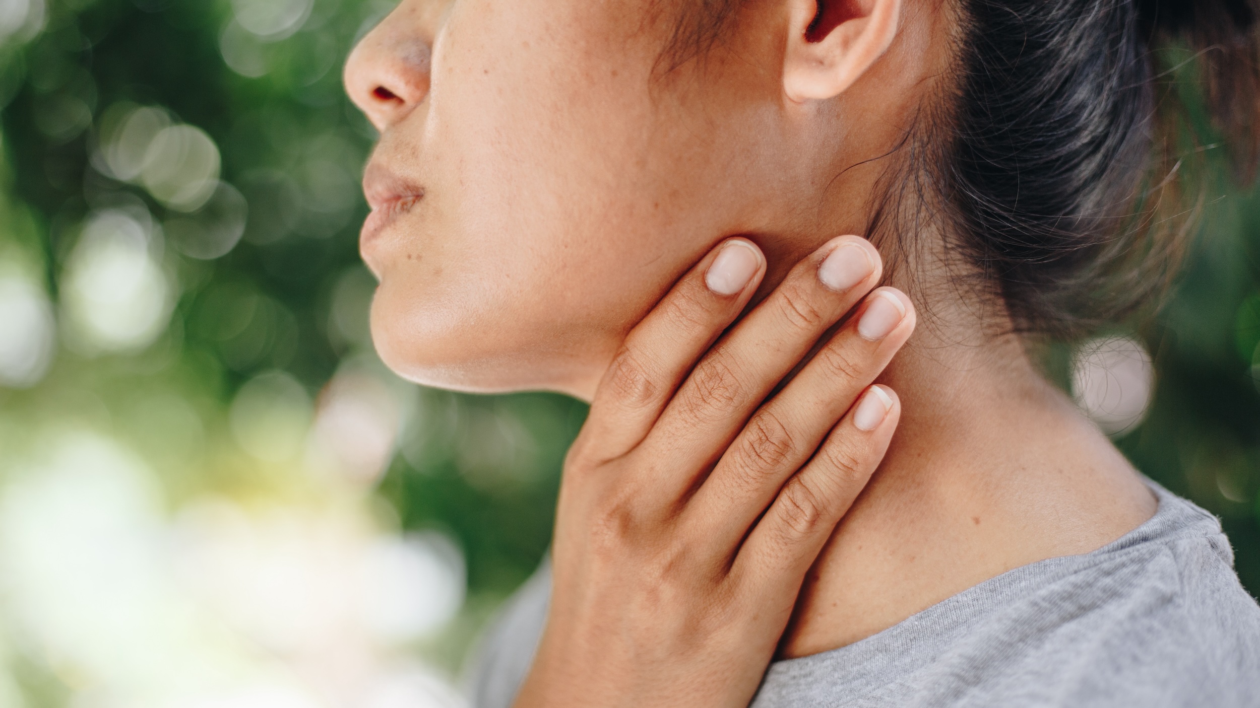 Close up of woman grabbing her neck in pain