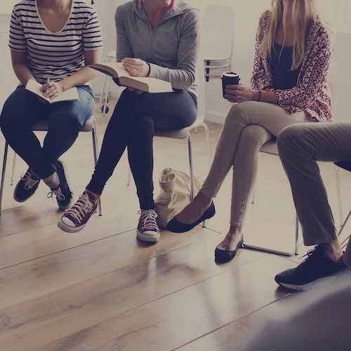 group of people sitting in a circle holding notebooks