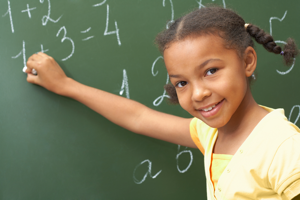 little girl standing by a chalkboard