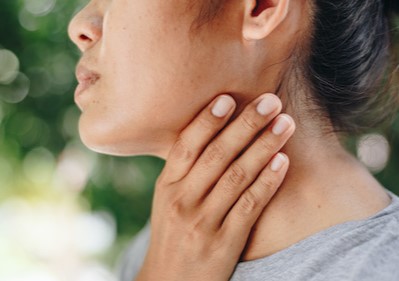 Woman grabbing her throat while standing outdoors | Rutgers Cancer Institute of New Jersey