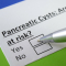 Hand holding a pen posed to fill out health questionnaire about pancreatic cysts